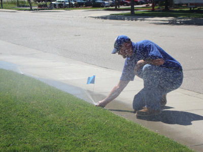 a Pickering sprinkler repair tech is adjusting a sprinkler head